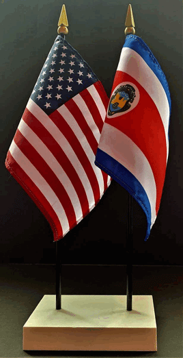 a photo of two miniature flags standing in a rectangular base: the left flag is the american flag, and the right flag is the flag of Costa Rica